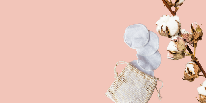 white cotton pads with a mesh bag laying on a pink background 