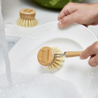 bamboo dish brush with handle cleaning a plate in soapy water