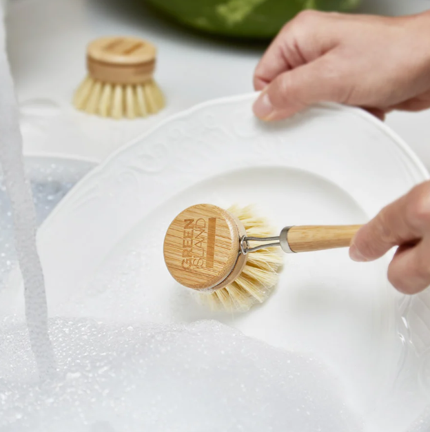 bamboo dish brush with handle cleaning a plate in soapy water